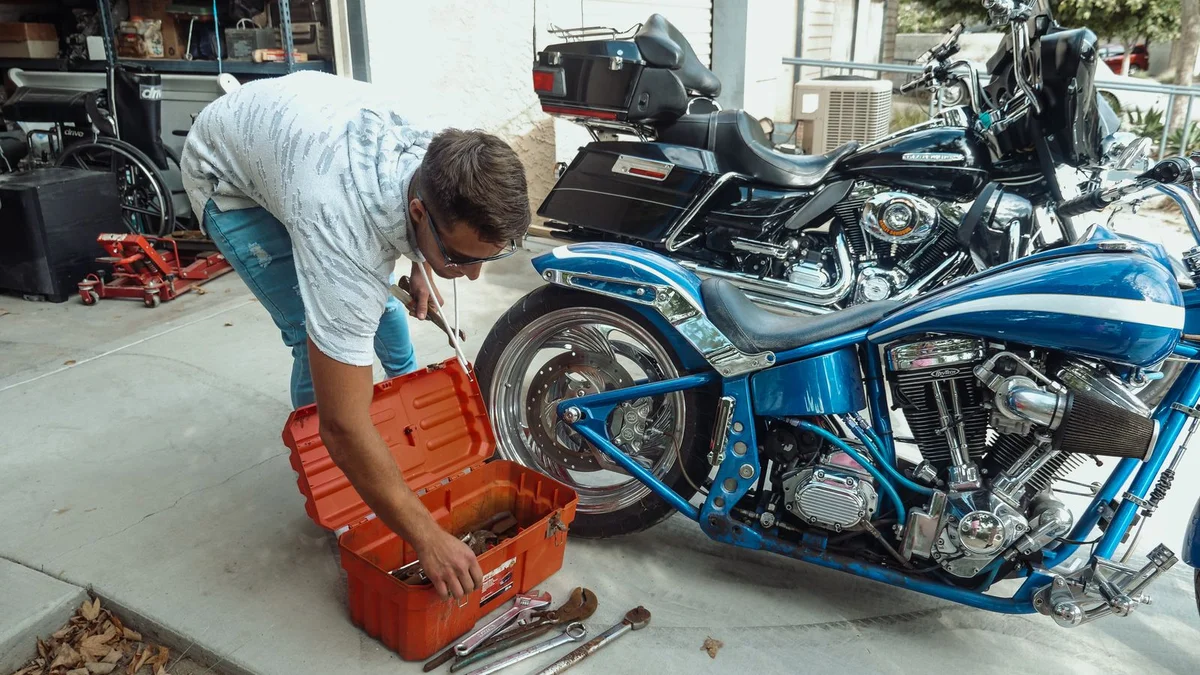 Mechanic working on a motorcycle in a garage with tools, representing rising parts and service costs from US-Canada tariffs in 2026