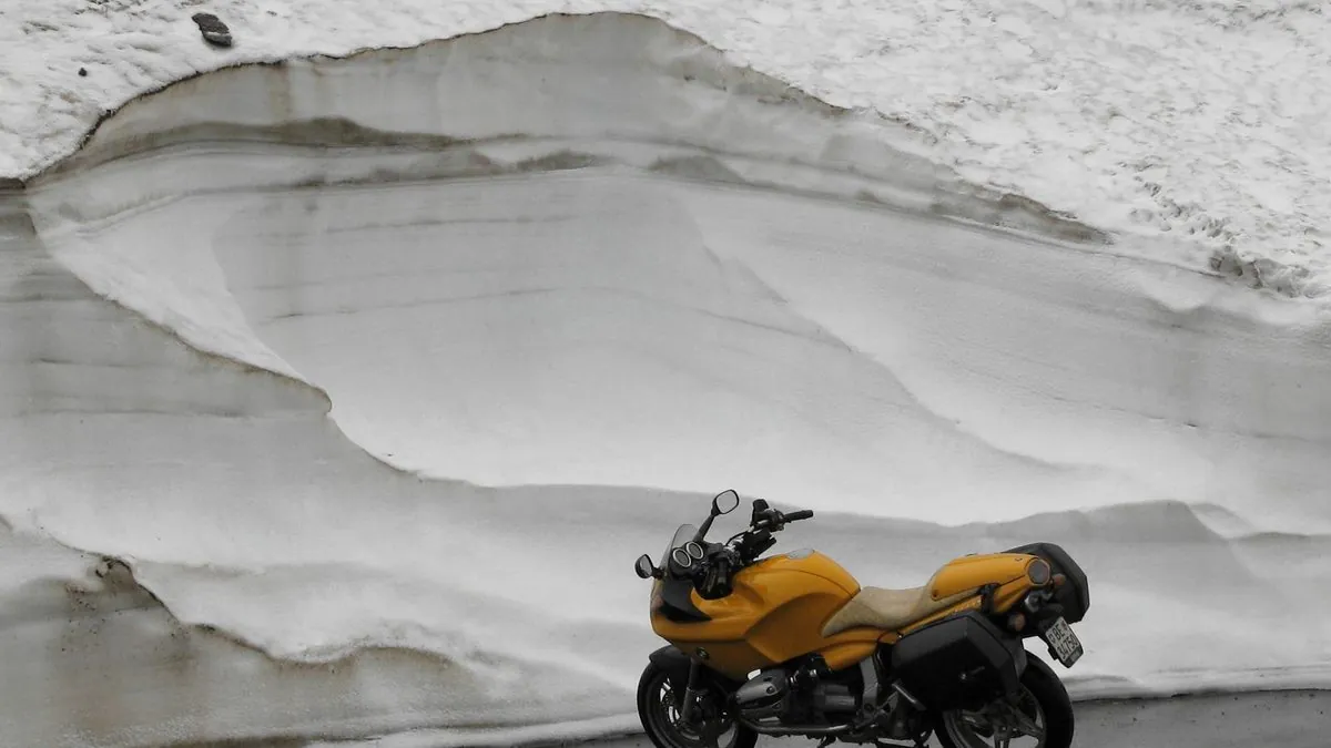 Motorcycle rider in full winter gear riding on a snow-dusted Atlantic Canada road